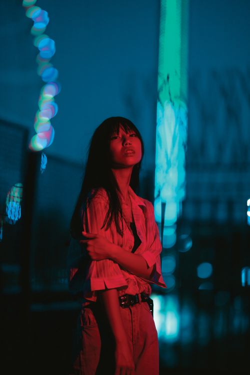 Free An atmospheric night portrait of a woman illuminated by colorful neon lights in the city. Stock Photo