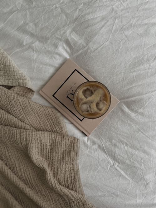 Free Relaxing morning setup with iced coffee on book on crumpled bed. Stock Photo