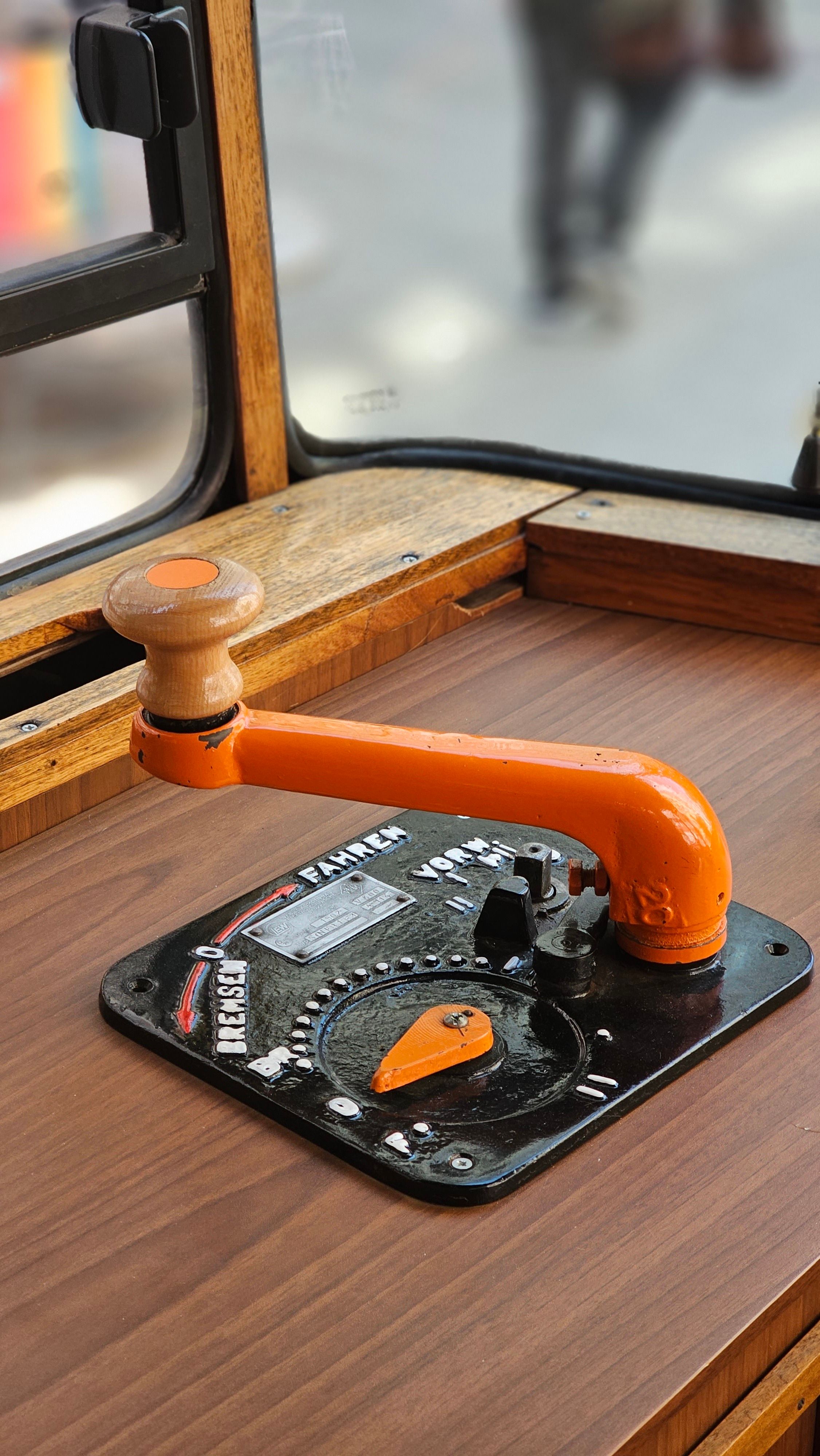 Fotomural Primer plano de una palanca de control de tranvía vintage con un mango naranja dentro de un vehículo clásico.
