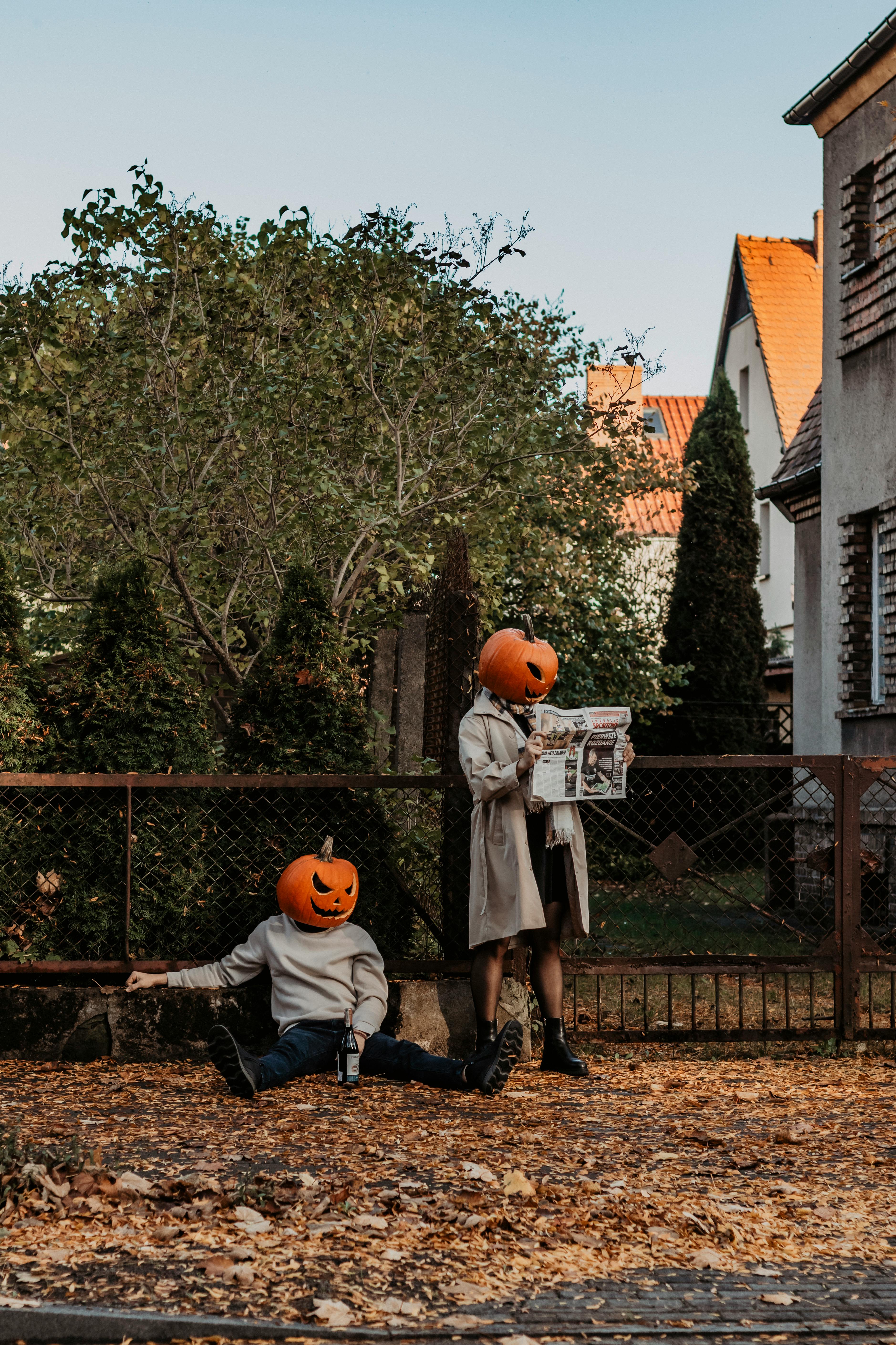 people with pumpkin heads sitting and standing near fence