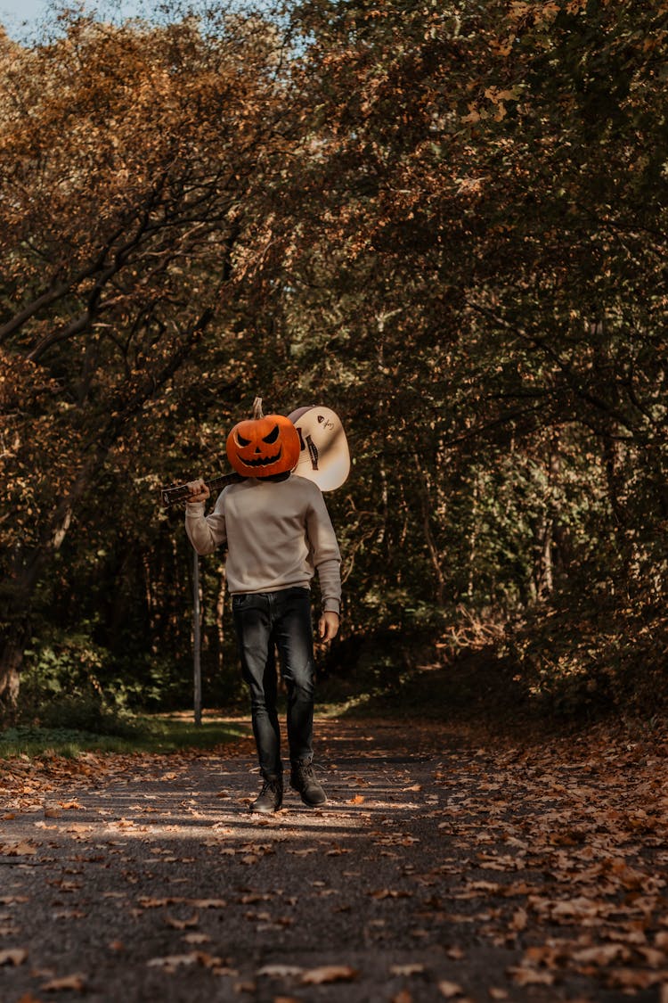 Person With Pumpkin Head Standing Among Trees In Fall