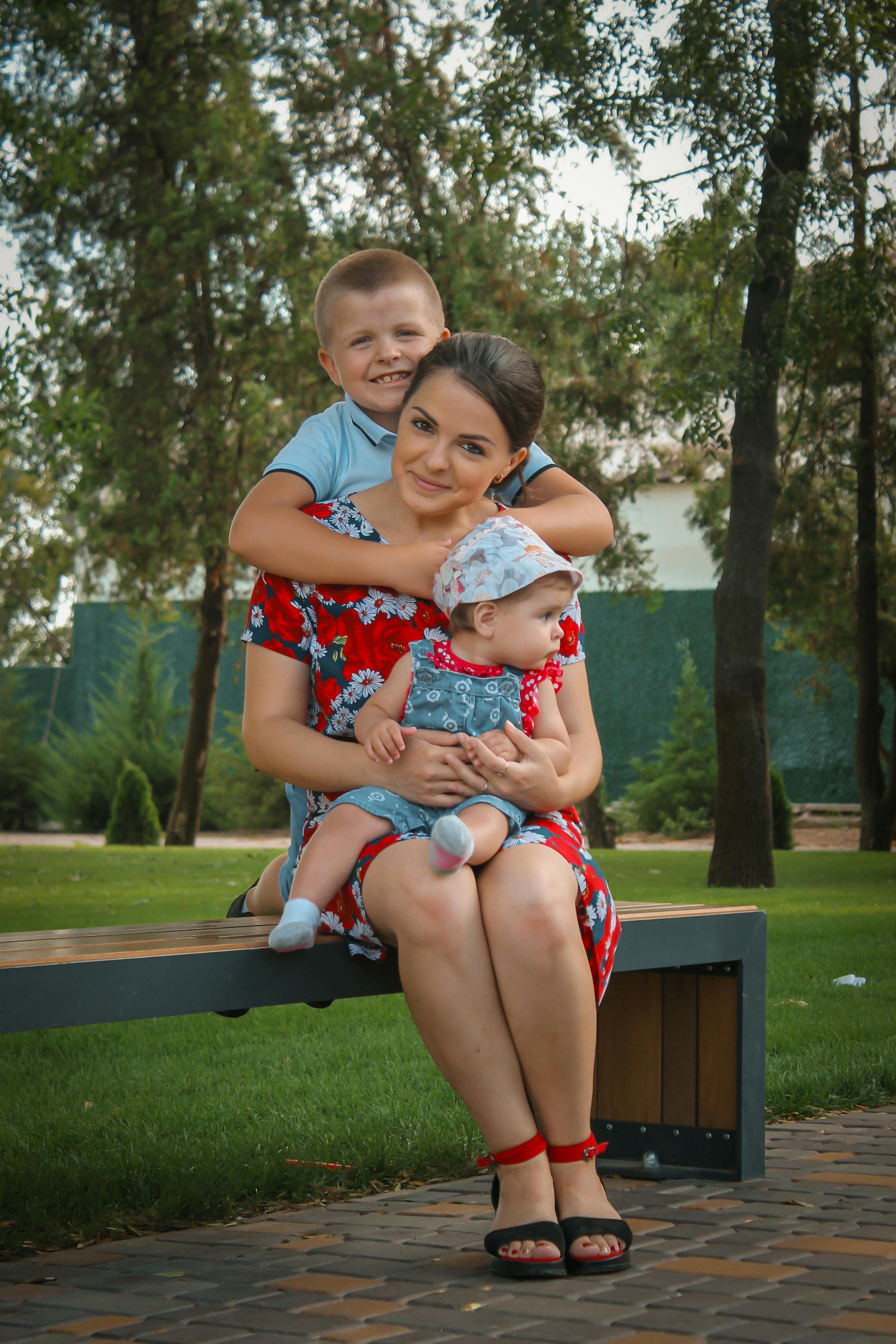 smiling woman sitting with children on bench in park