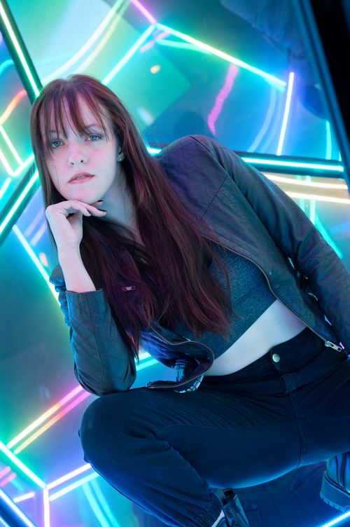 Free Woman posing in neon-lit space, showcasing edgy fashion style. Stock Photo