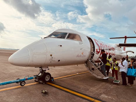 A group of people board a small aircraft on an airport tarmac under a cloudy sky.
