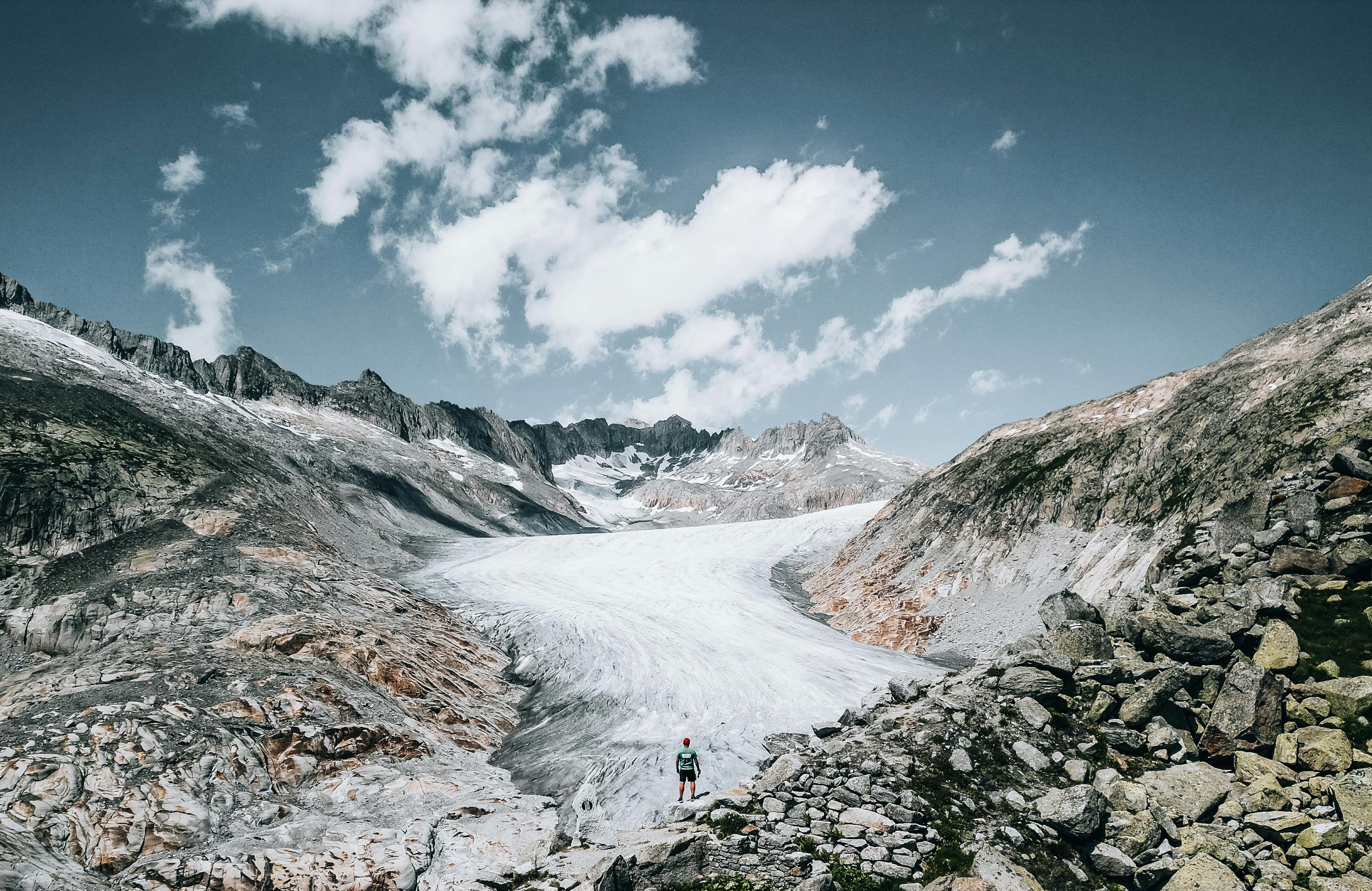 一位旅客在瑞士阿爾卑斯山腳下打包保暖衣物和登山裝備，背景是雪覆蓋的山峰和冰川