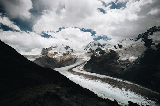 Stunning view of snowcapped mountains and glacier under a dramatic sky.