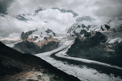 Free Breathtaking landscape of snowcapped mountains and glacier under dramatic clouds. Stock Photo