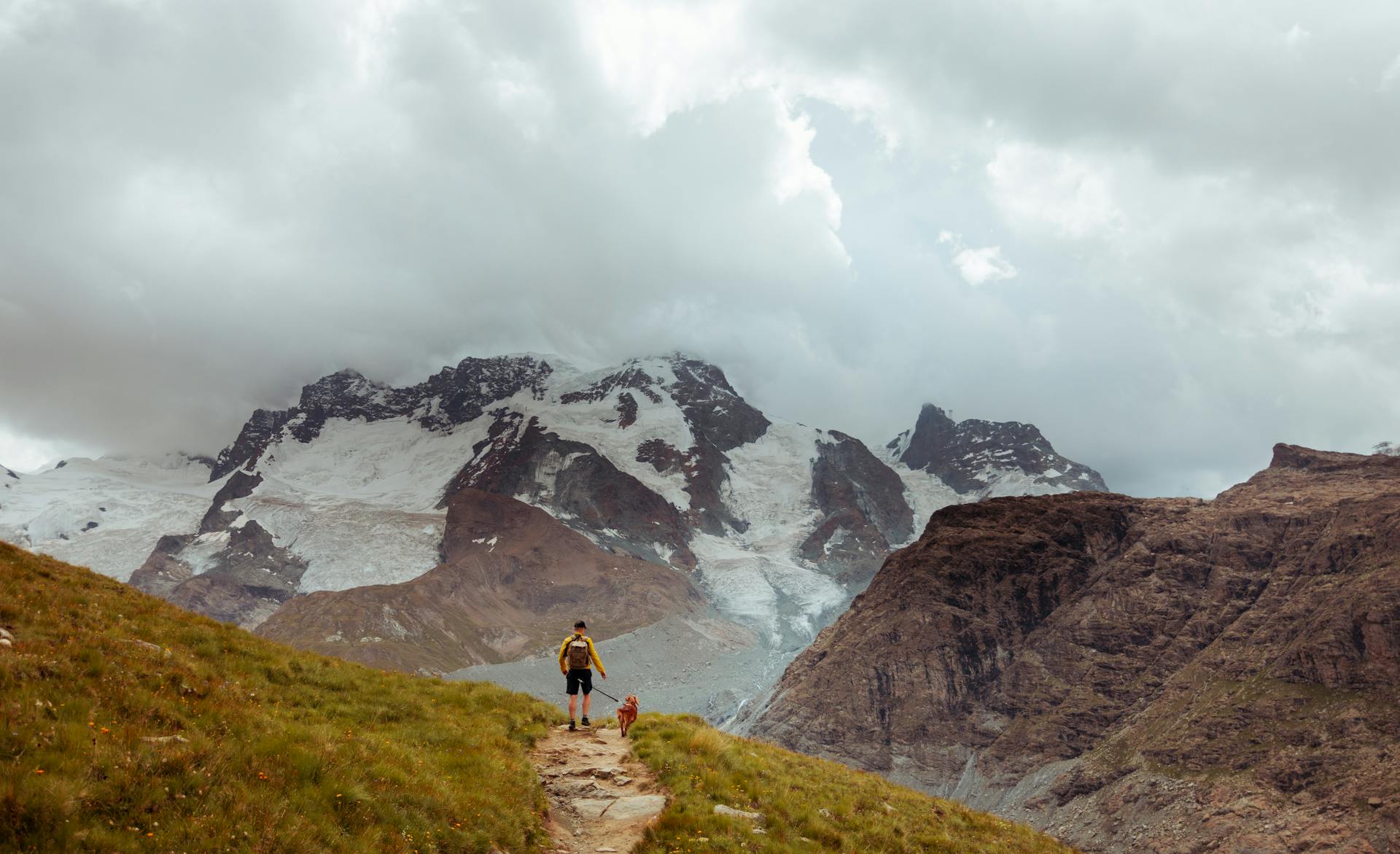 A Man with a Dog Walking in Mountains