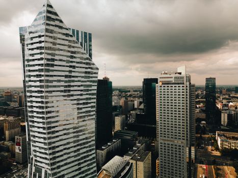 Aerial view of the modern Warsaw skyline with striking skyscrapers and dramatic clouds.