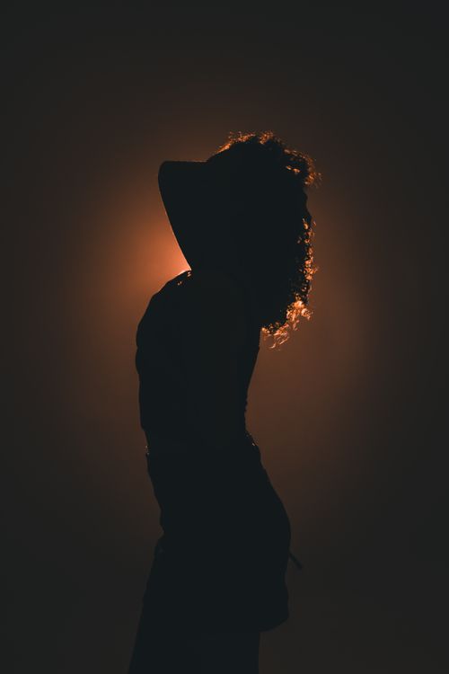 Free Artistic silhouette of a woman wearing a hat against a vibrant sunset backdrop. Stock Photo