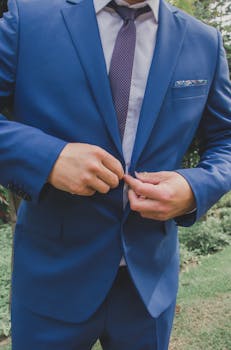 Elegant man in blue suit adjusting jacket outdoors, showcasing fashion and style.
