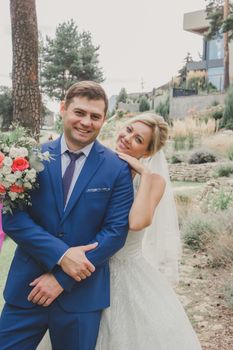Happy bride and groom posing outdoors in elegant attire, capturing the essence of a beautiful wedding day.