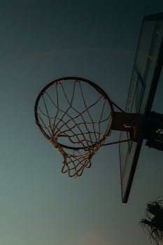 A basketball hoop silhouetted against the twilight sky, capturing the essence of outdoor sports