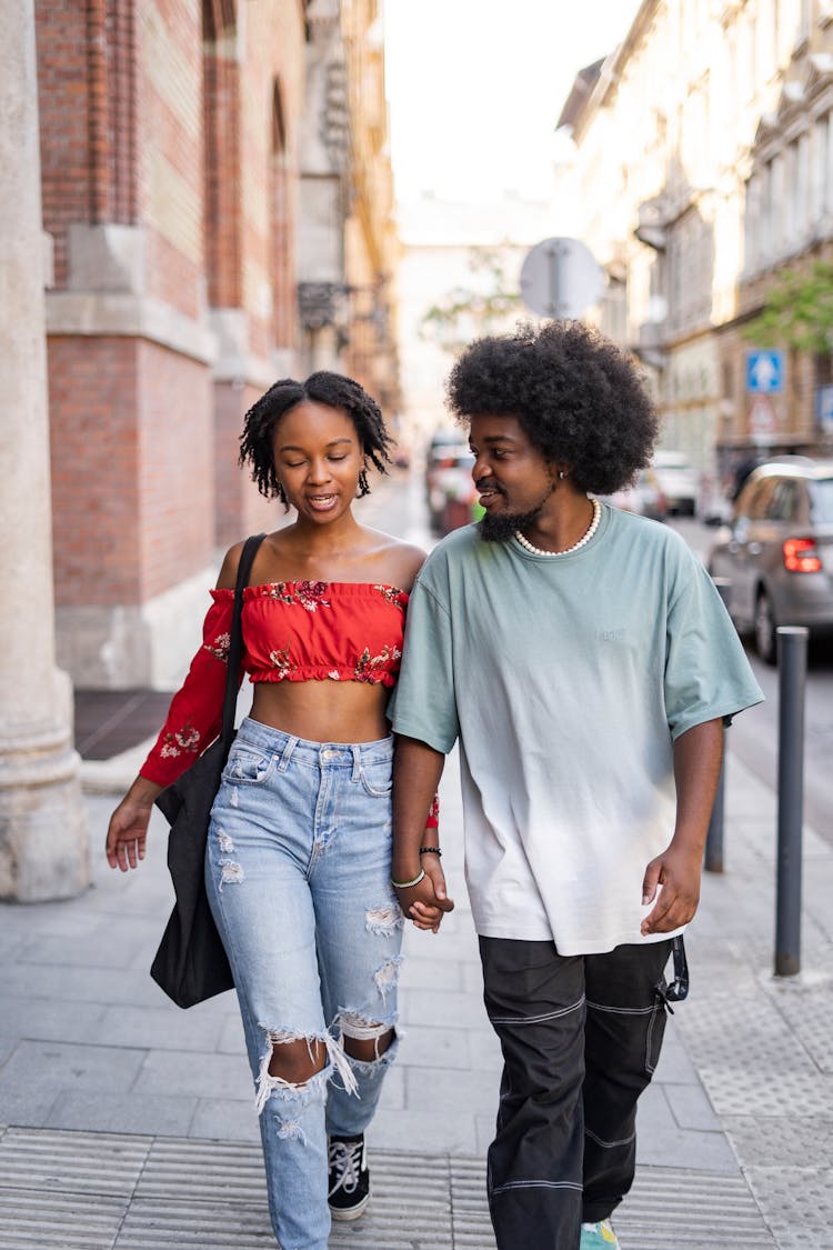 Young Woman And Man Walking On A Street Hand In Hand