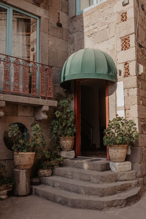Free Entrance of a traditional stone building with plants and a green canopy, showcasing classic architecture. Stock Photo