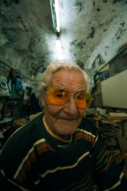 Portrait of an elderly man wearing yellow sunglasses in a rustic workshop setting, Alegria, Philippines.