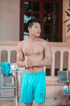Young man enjoying leisure by the poolside in summer, embracing relaxation.