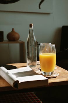 A warm, inviting scene of a book and orange juice on a wooden table, perfect for relaxation.