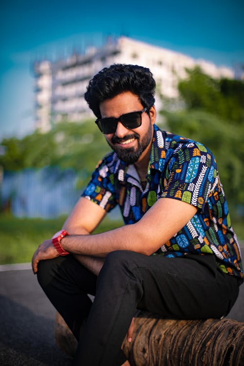 Smiling Man in Wayfarer Sunglasses and Multi Colored Short Sleeved Shirt