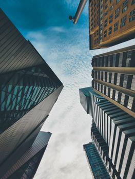 Dynamic upward view of modern skyscrapers and blue sky in urban setting.