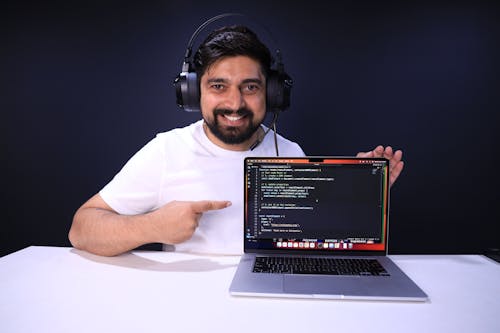 Man in Headphones Showing Programming Process on a Laptop