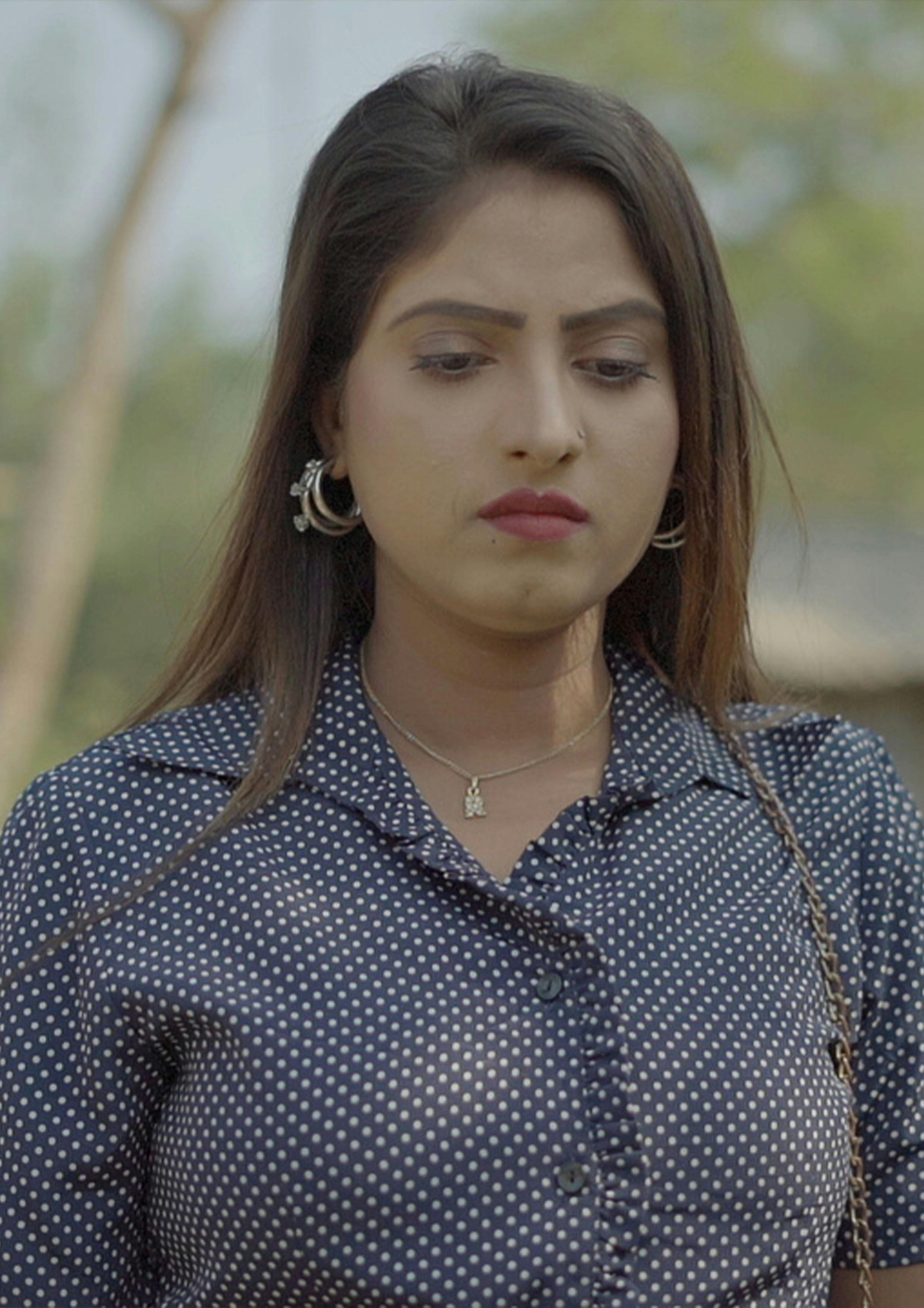 Woman outdoors with a contemplative expression in a polka dot shirt, capturing a thoughtful moment.