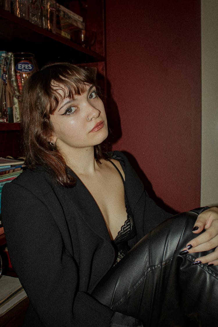 Young Woman In A Black Outfit Sitting In A Room 