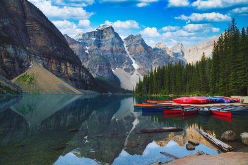 Free Vibrant kayaks rest on the calm waters of Moraine Lake, surrounded by breathtaking mountains in Banff National Park. Stock Photo