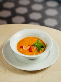 A bowl of vibrant tomato soup garnished with herbs, perfect for a cozy meal.