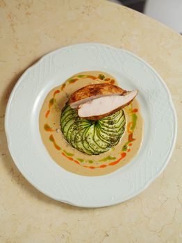 Delicious roasted chicken with zucchini on a creamy sauce, beautifully plated.