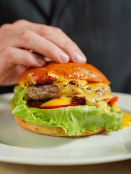 Close-up of a delicious cheeseburger with bacon and lettuce, ready to be enjoyed.