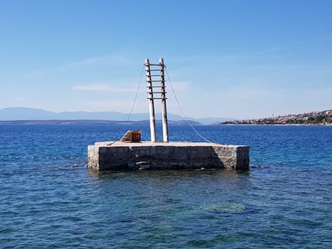 Peaceful coastal scene featuring a stone pier and calm blue ocean under a clear sky.