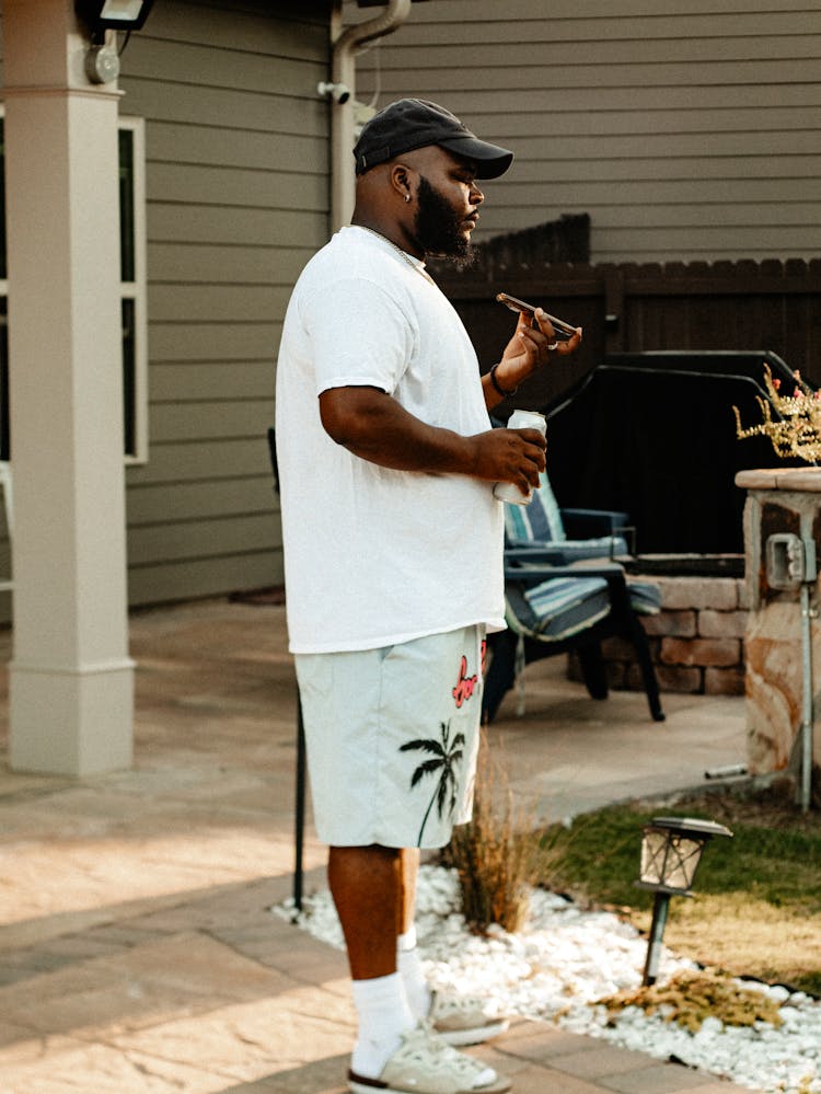 African Man Talking On A Phone In Front Of A House 