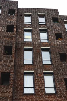 Vertical shot of a modern brick building facade with windows and architectural details.