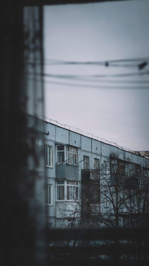 Free Moody view of urban apartment block through window on overcast day, capturing an introspective urban scene. Stock Photo
