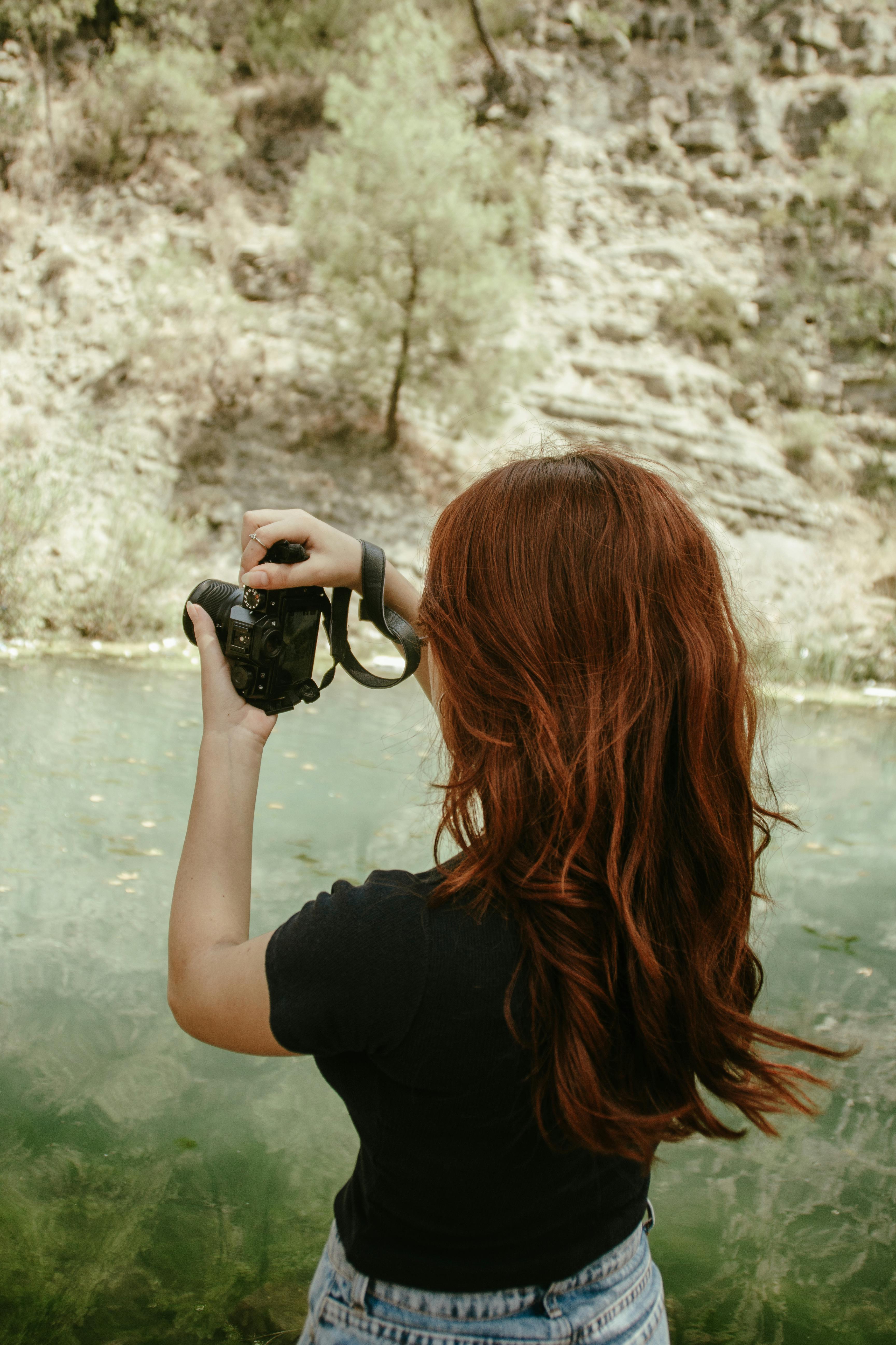 back view of woman taking pictures of lake