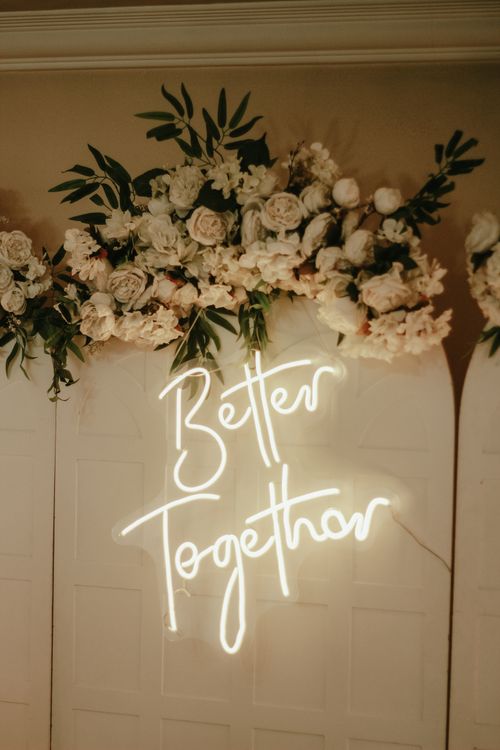 Free Beautiful wedding decor featuring floral arrangement and glowing 'Better Together' neon sign. Stock Photo