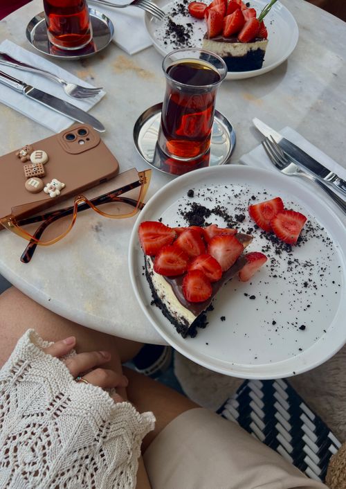 Free Top view of a marble table with strawberry cake and tea, smartphone and sunglasses. Stock Photo