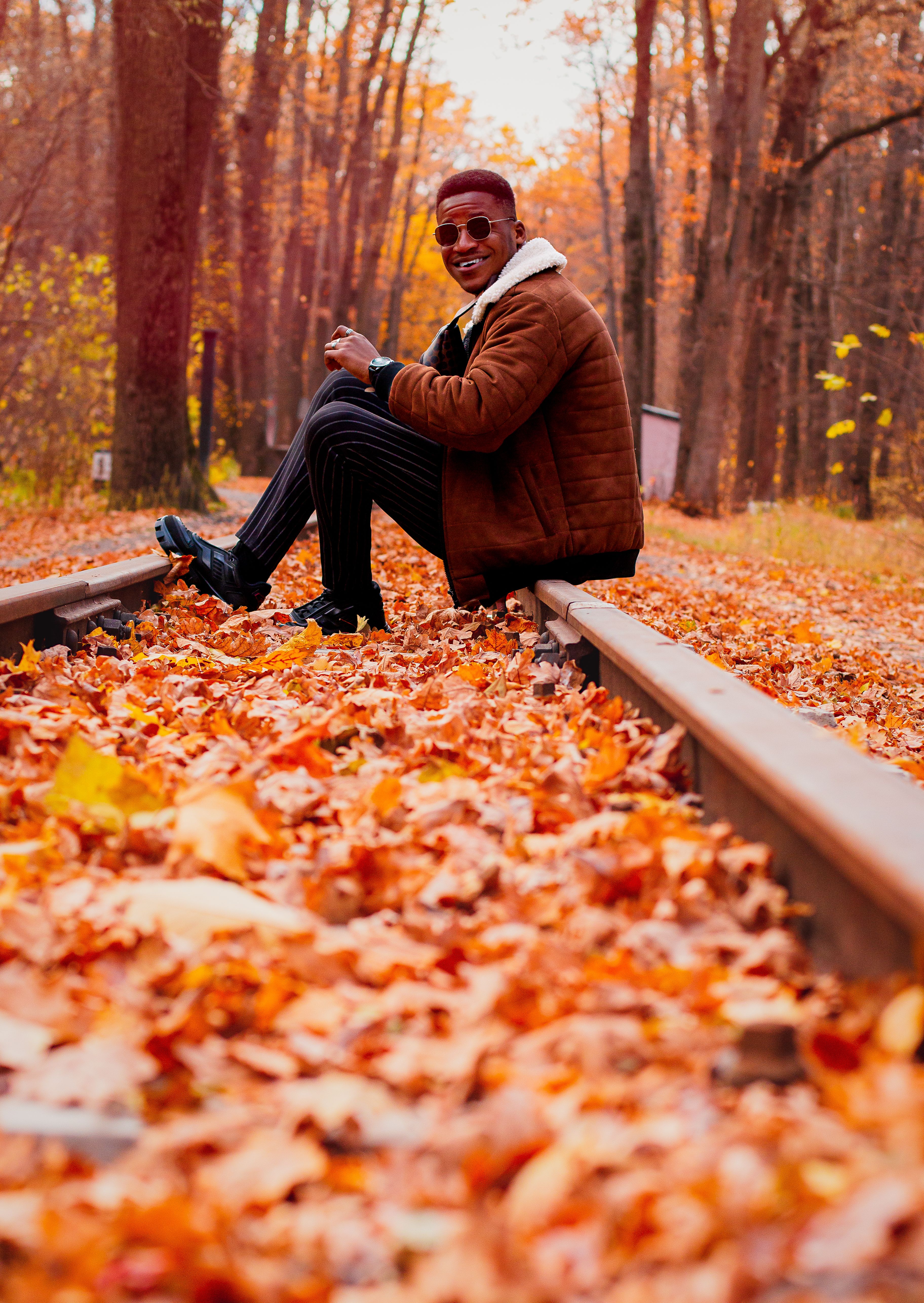 A Man Sitting on the Railway in the Forest in Autumn · Free Stock Photo