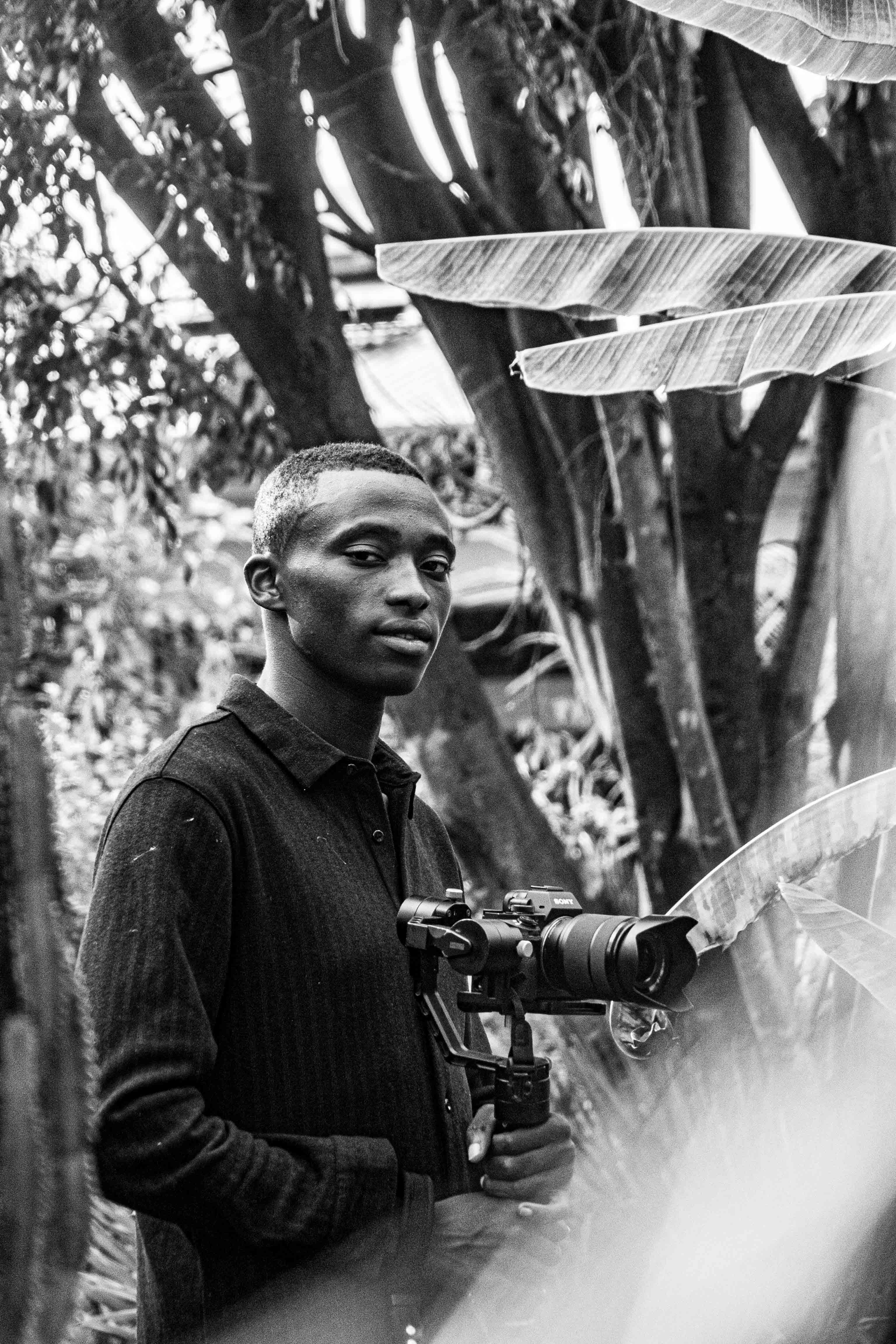 Black and white portrait of a male photographer outdoors with camera gear.