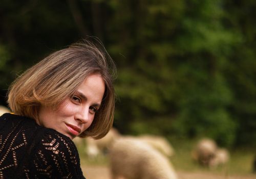 Free Woman outdoors with sheep in a lush green countryside setting. Stock Photo