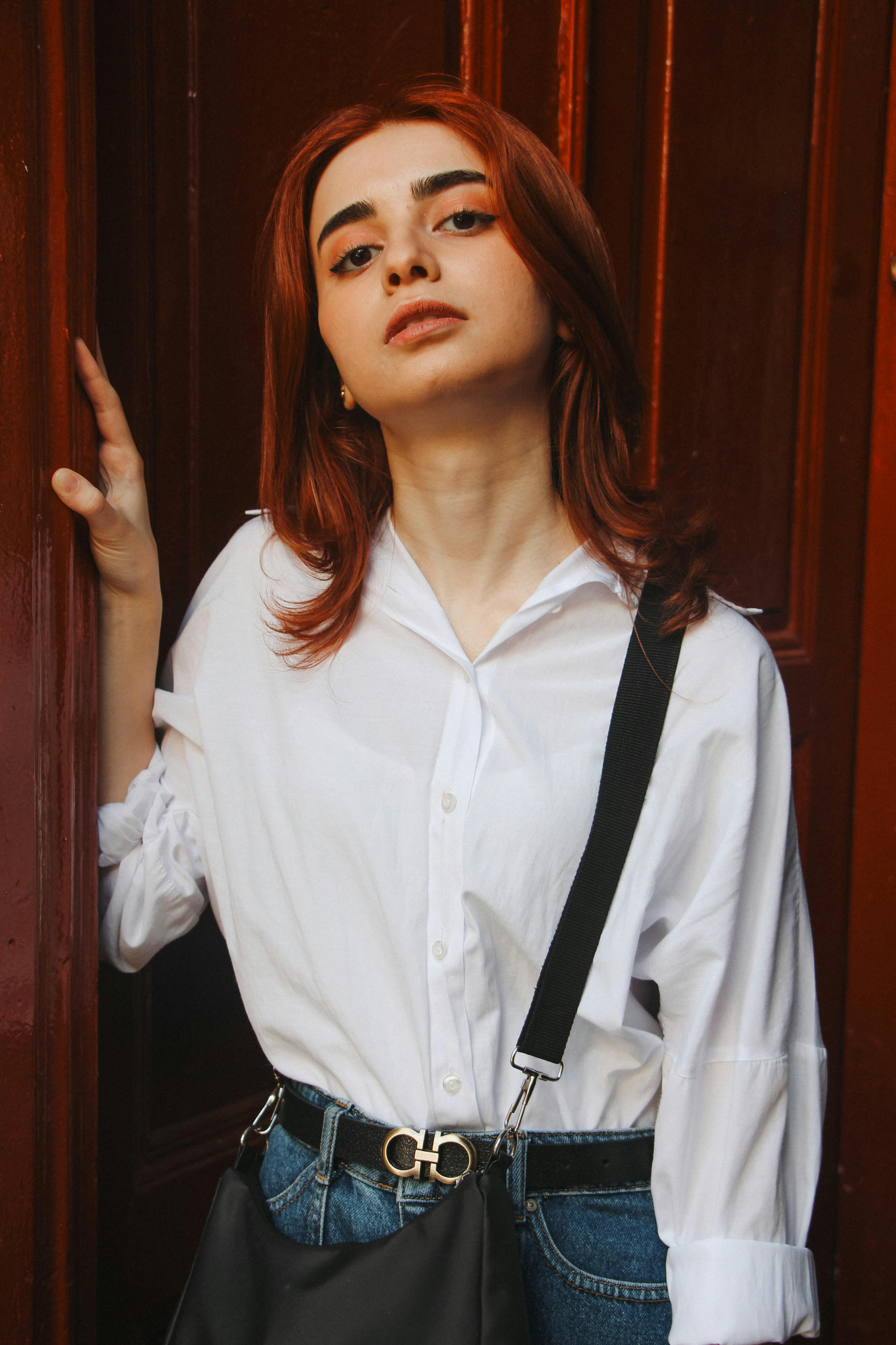 Stylish portrait of a young woman with red hair against a wooden door in Baku, Azerbaijan.