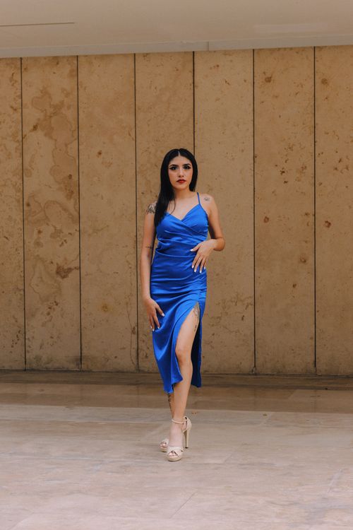 Free Fashion model in a striking blue dress posing against a textured wall, exuding elegance and style. Stock Photo