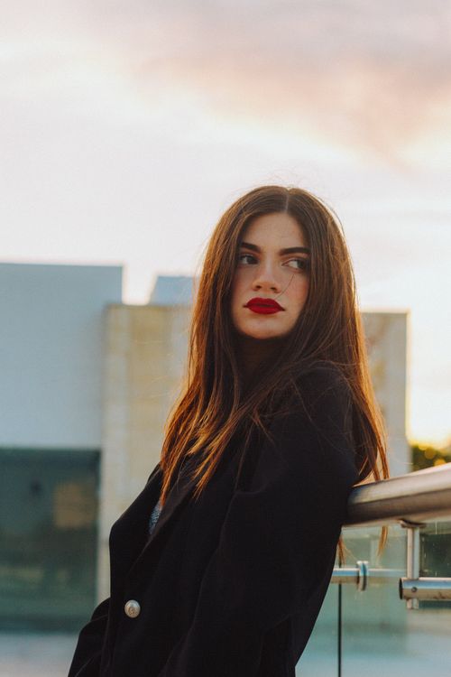Free Portrait of a fashionable woman standing outdoors at sunset. Stock Photo