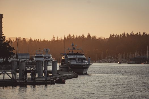 Tranquil sunset over Vancouver harbor with boats and forest in view.