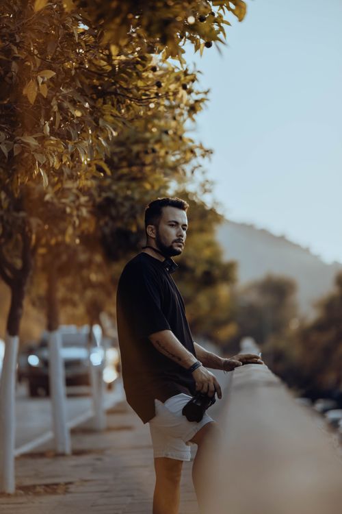 Free Portrait of a man standing by a scenic street, embracing casual fashion in a natural setting. Stock Photo