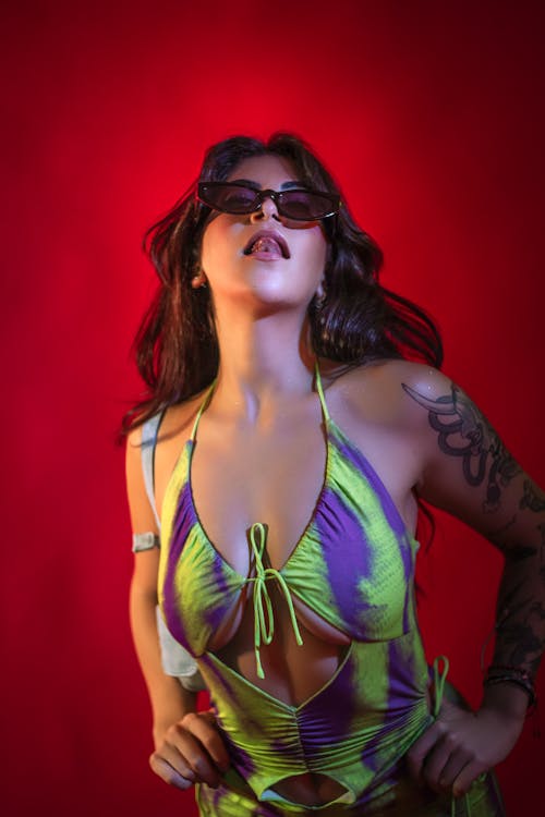 Young Woman with Tattoos Posing in a Dress against Red Background 