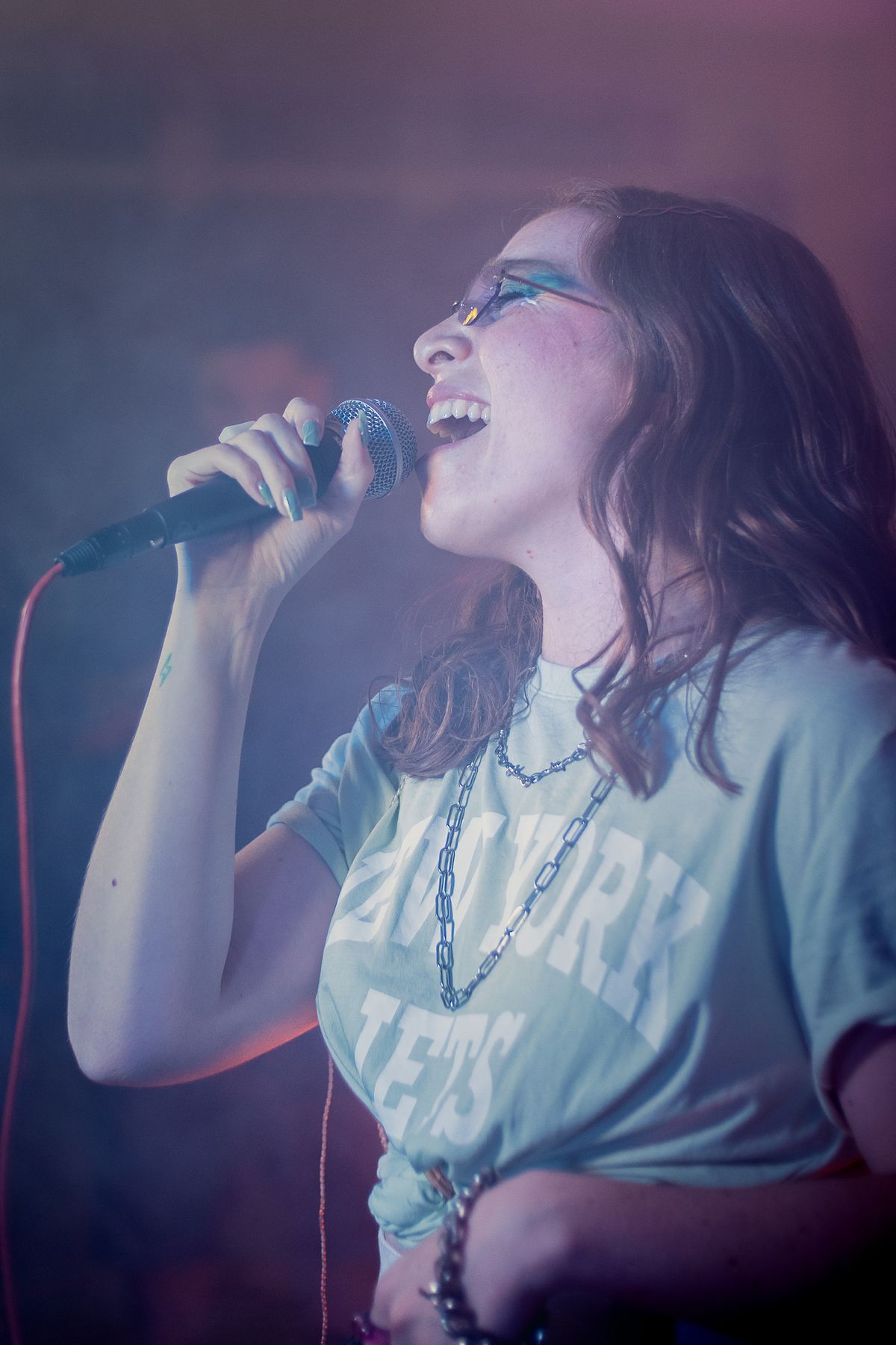 Female singer performing on stage under coloured concert lights