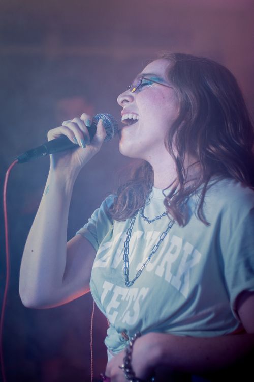 Free A dynamic concert photo of a female singer passionately performing with a microphone under colorful stage lights. Stock Photo
