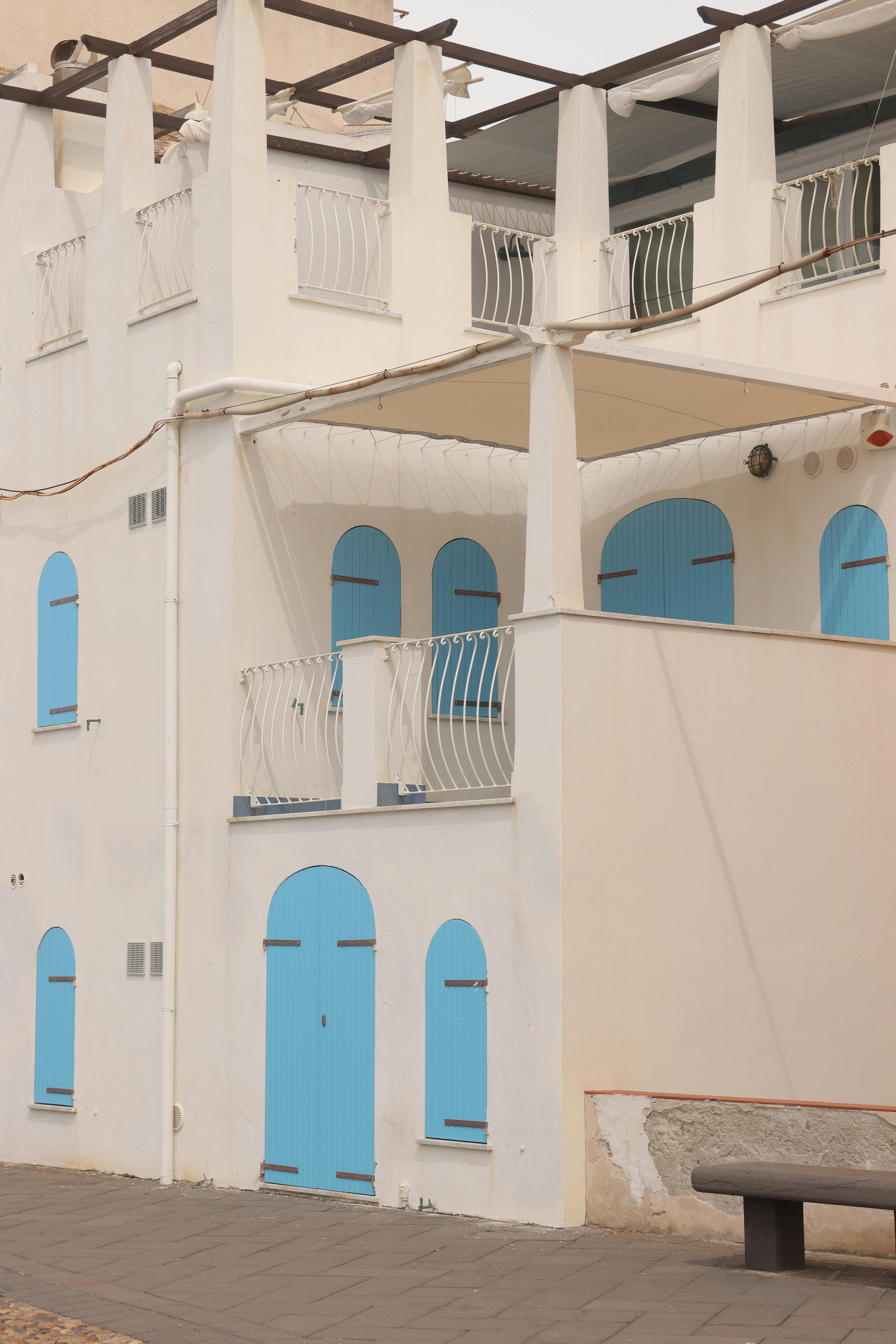 Elegant white building with distinctive blue shutters and door in Alghero, Sardinia, Italy.
